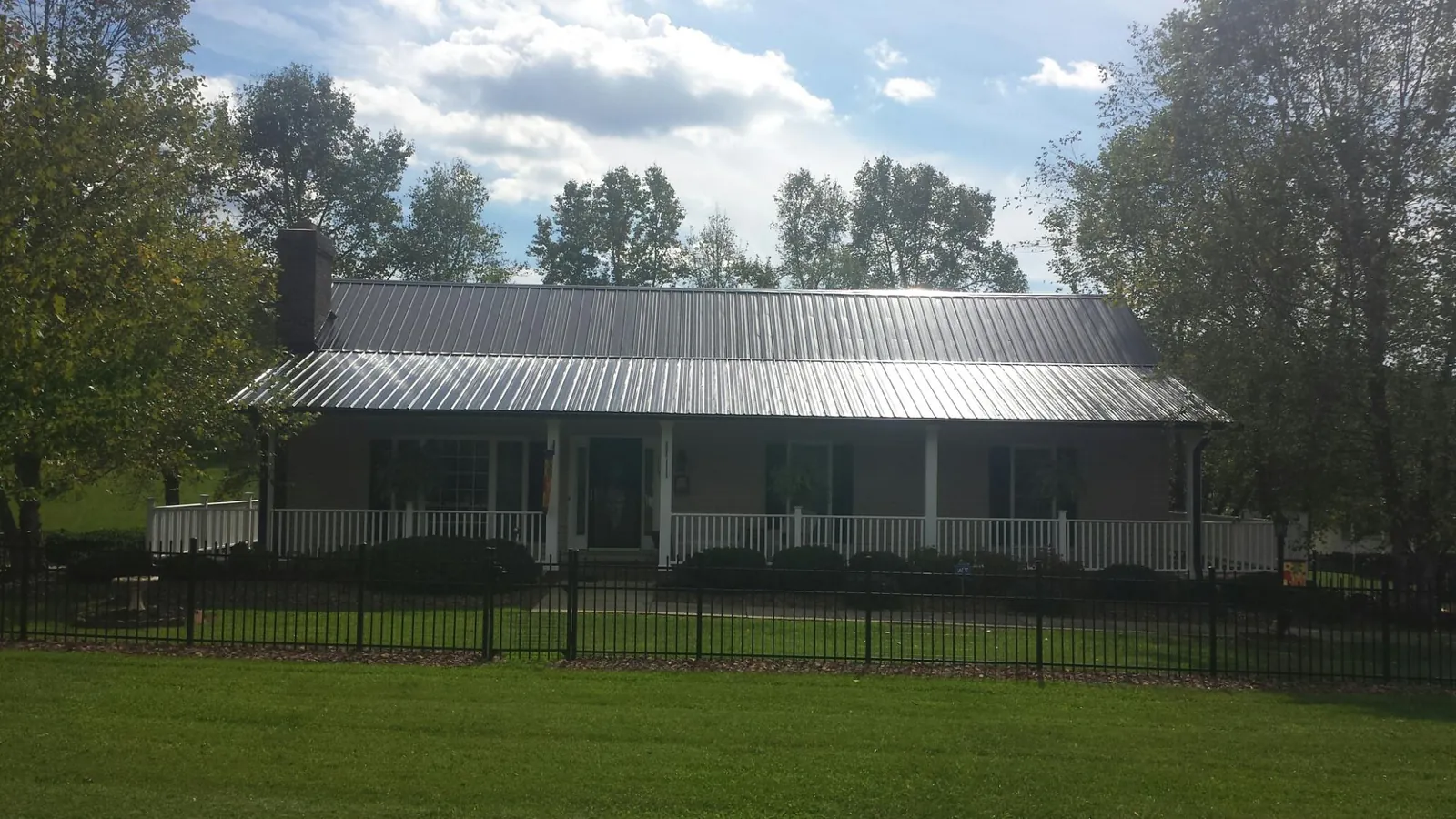 Gray metal roof on a brick ranch with a full width front porch — Gutter Guard Installation work by our crew in Henderson